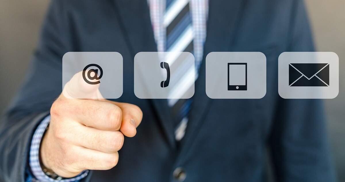 Mann steht vor Monitor mit vier Buttons und tippt auf das @