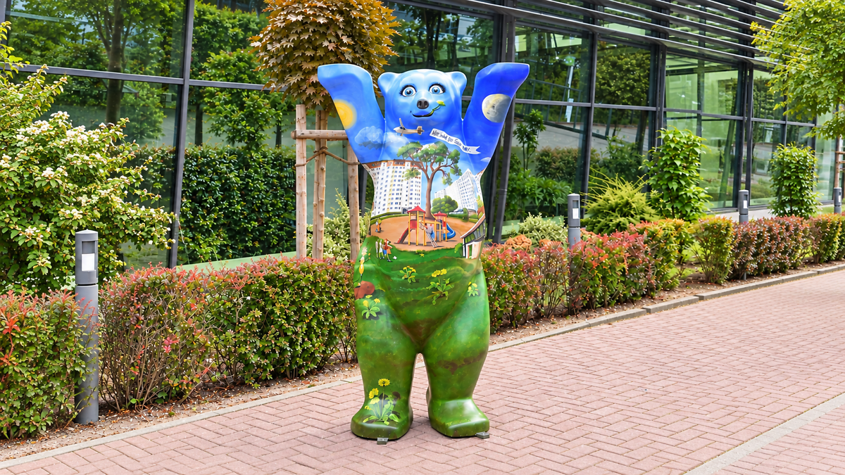 Festgelände der WBG mit einem großen blau-weißen aufblasbaren Winkemann im Vordergrund. Im Hintergrund sind Verkaufsstände, Sitzbereiche, Besucherinnen und Besucher sowie Wohngebäude zu sehen.